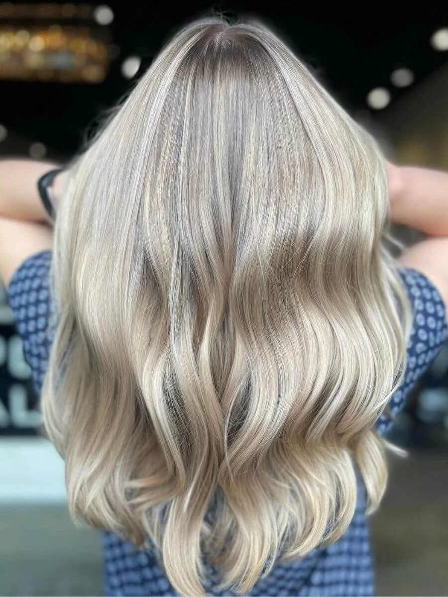 Back view of a woman with long, wavy blonde hair.