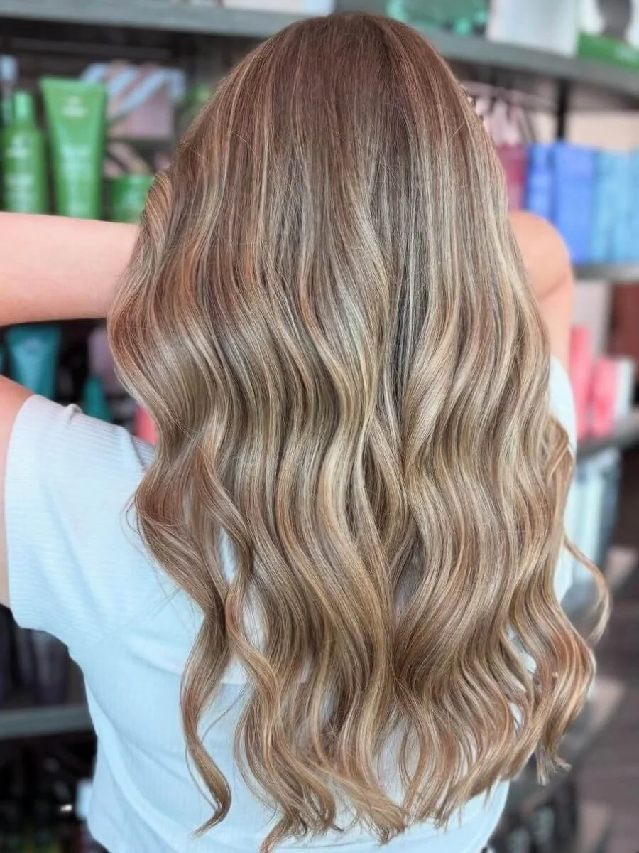 Back view of a woman with long, wavy blonde hair in a retail store.