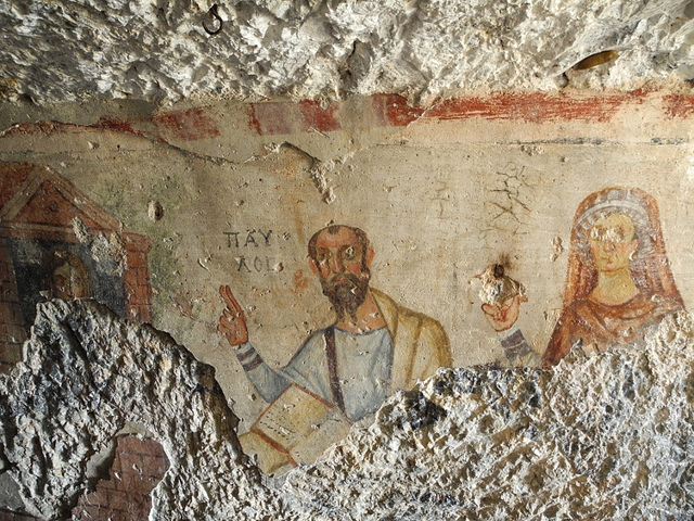 Fig. 2.19: Fresco of Paul and Thecla near Ephesus, 6th century CE. Both are portrayed as equals. Probably influenced by a the 2nd century writing Acts of Thecla, they share the same height and teaching posture, but Thecla’s eyes and hand are disfigu…