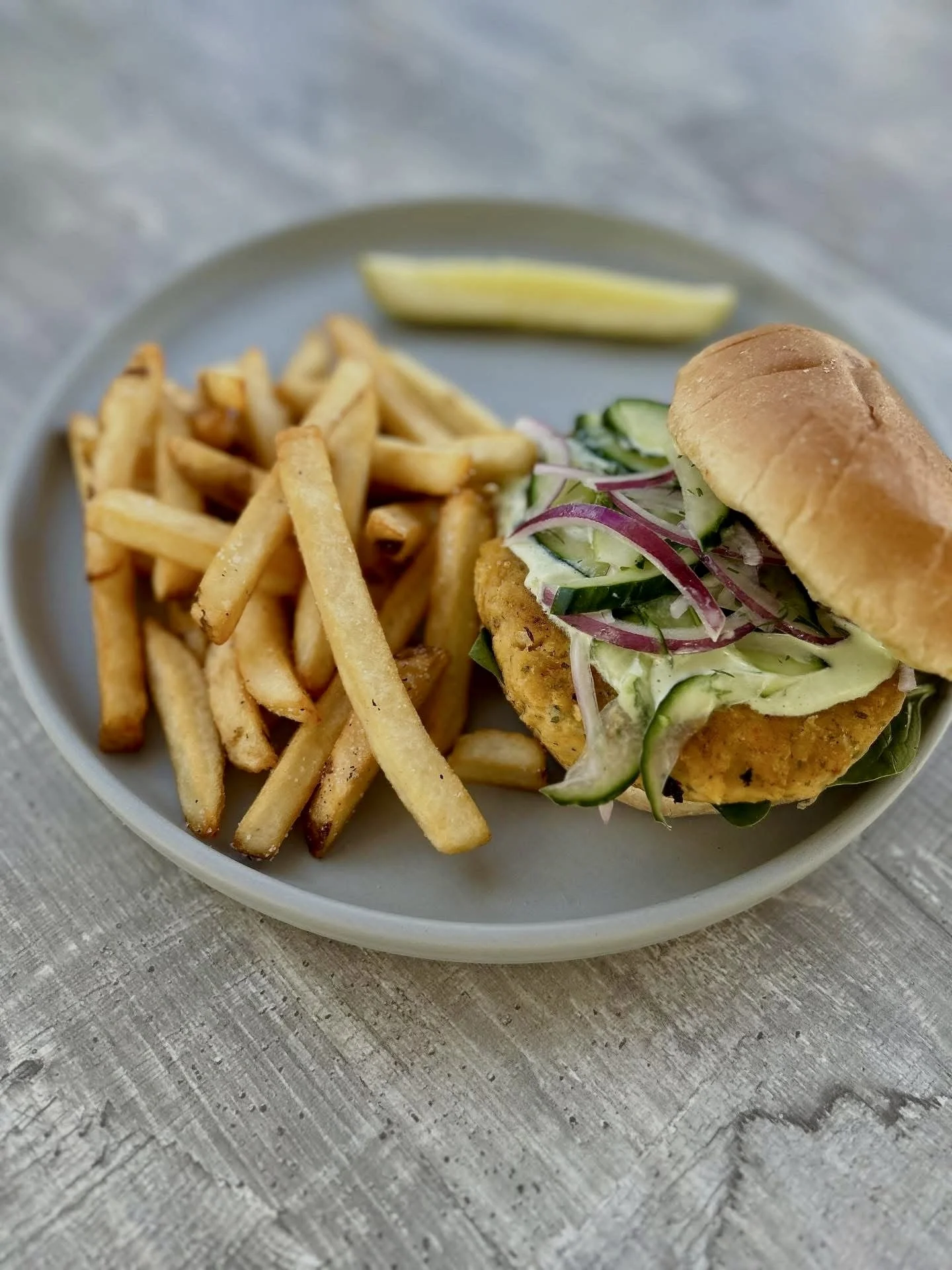 Pine Point Grill's sweet potato and chickpea burger featuring baby spinach, cucumber slaw, red onion, tzatziki sauce, on a potato roll. 