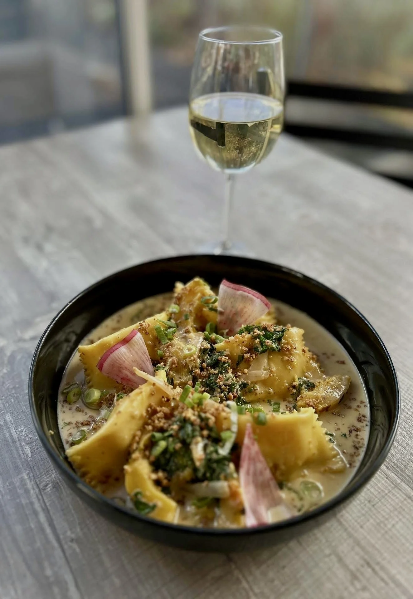 Pine Point Grill's butternut squash agnolotti featuring sage cream sauce, delicata squash, kale, and sea salt toasted walnuts. 