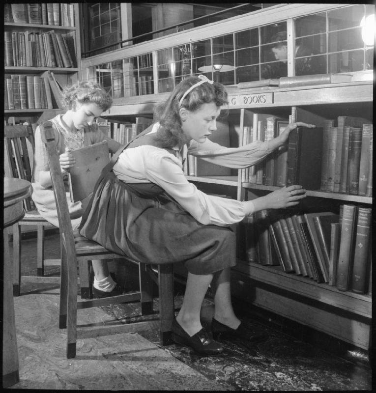 Two young female library assistants rearrange and classify books at Leytonstone Public Library, Church Lane. 1944.