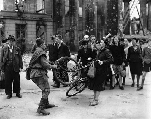 Russian soldier tussling with a bicycle in Berlin, 1945