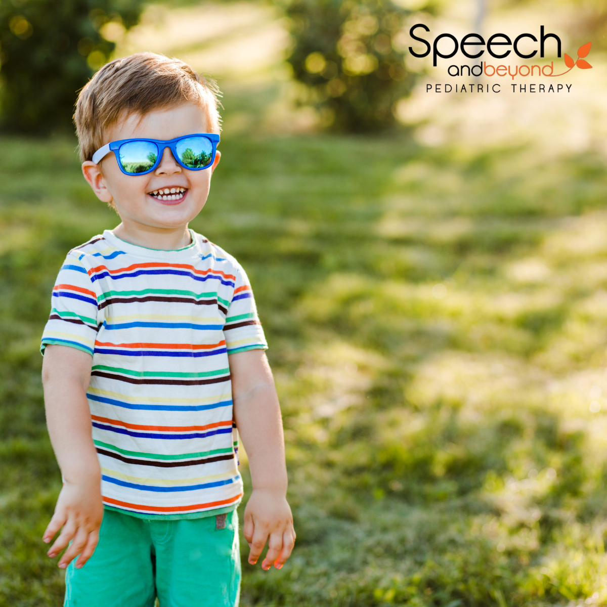 a young boy with blue sunglasses smiling, outside