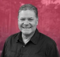 Fred Dojan, Senior Consultant of Footwear Innovation at Zefyr Consulting, smiling at camera with a pink overlay background.