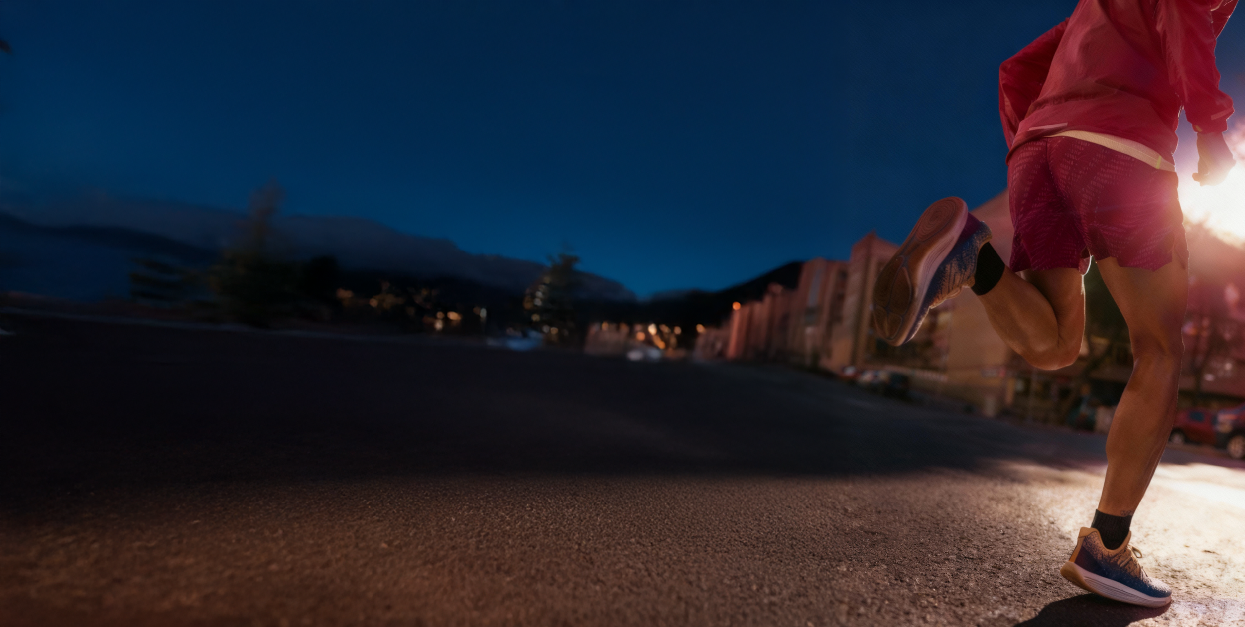 A person in athletic gear running down a city street at sunset, shown from a low angle with a warm pink and purple color overlay.