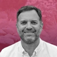 Dave Kelley, Principal at Zefyr Consulting, smiling at camera with a pink overlay background.