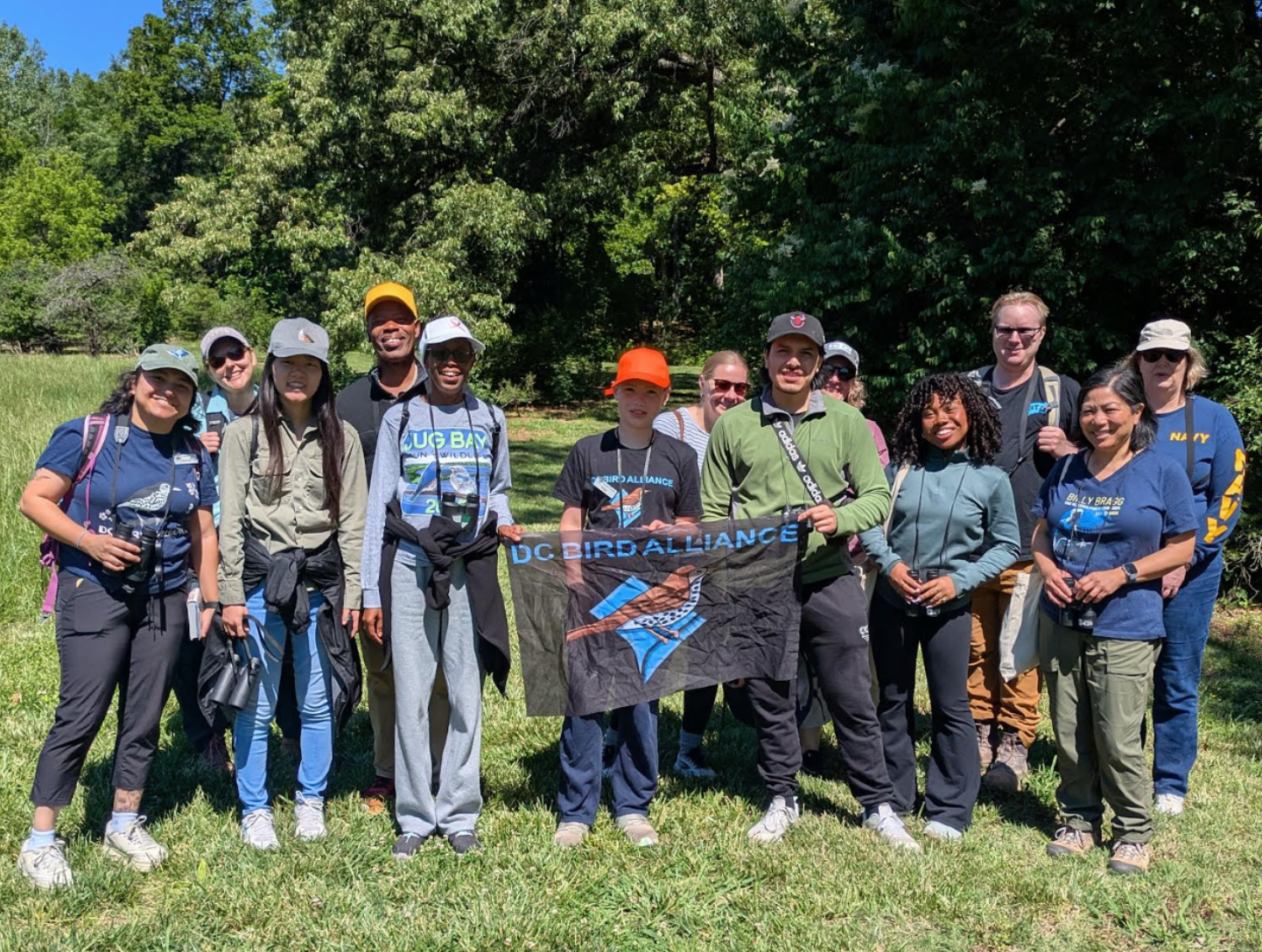 Photo showing a group of people outside smiling and holding a "DC Bird Alliance" flag