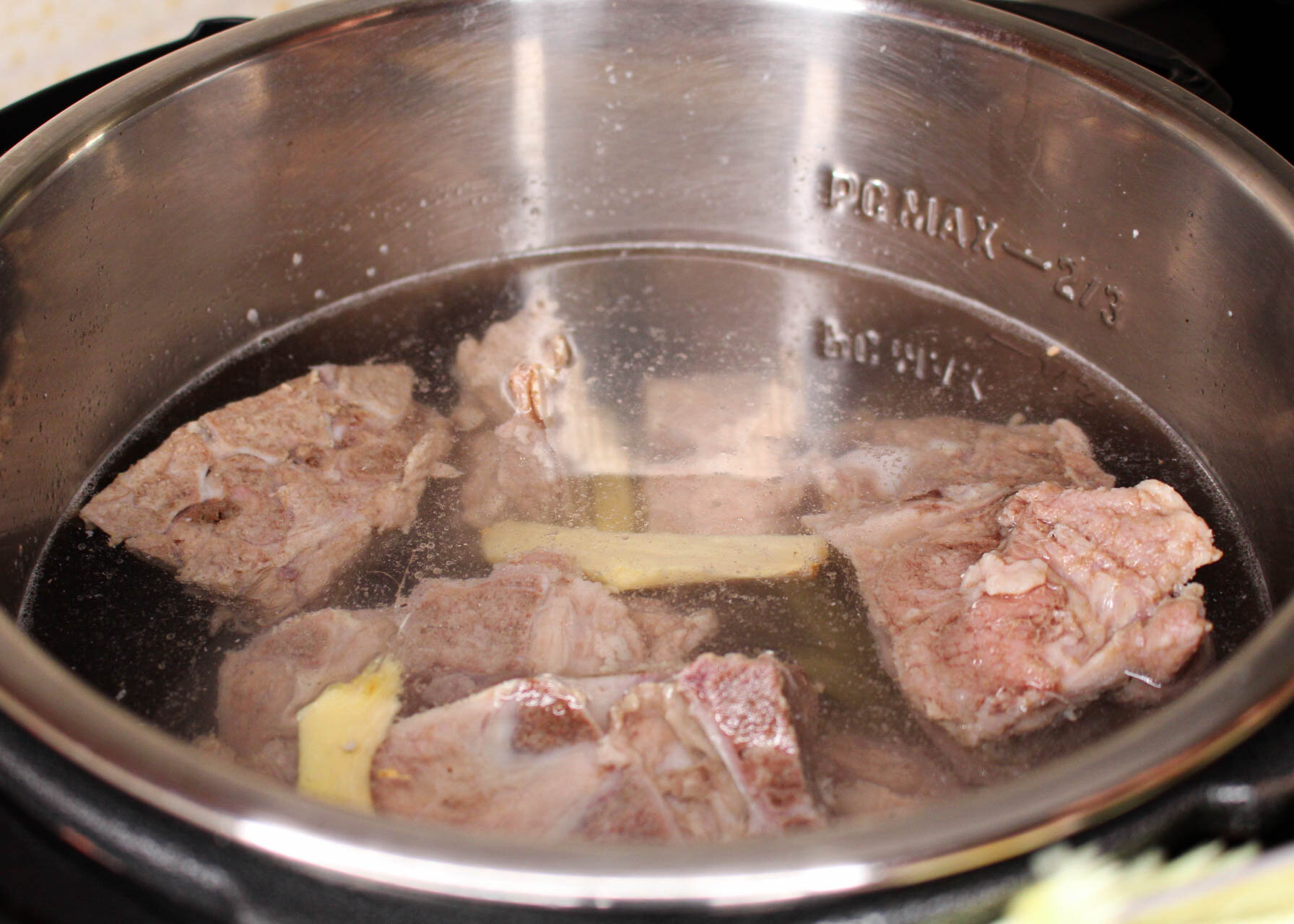 Add pork neck bones and sliced ginger into the instant pot.
