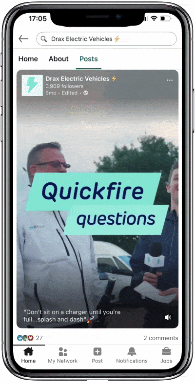 A smartphone screen displaying a social media post from Drax Electric Vehicles with the text "Quickfire questions" on it. Behind the overlay, there are two men outdoors, one holding a microphone, with vehicles in the background.