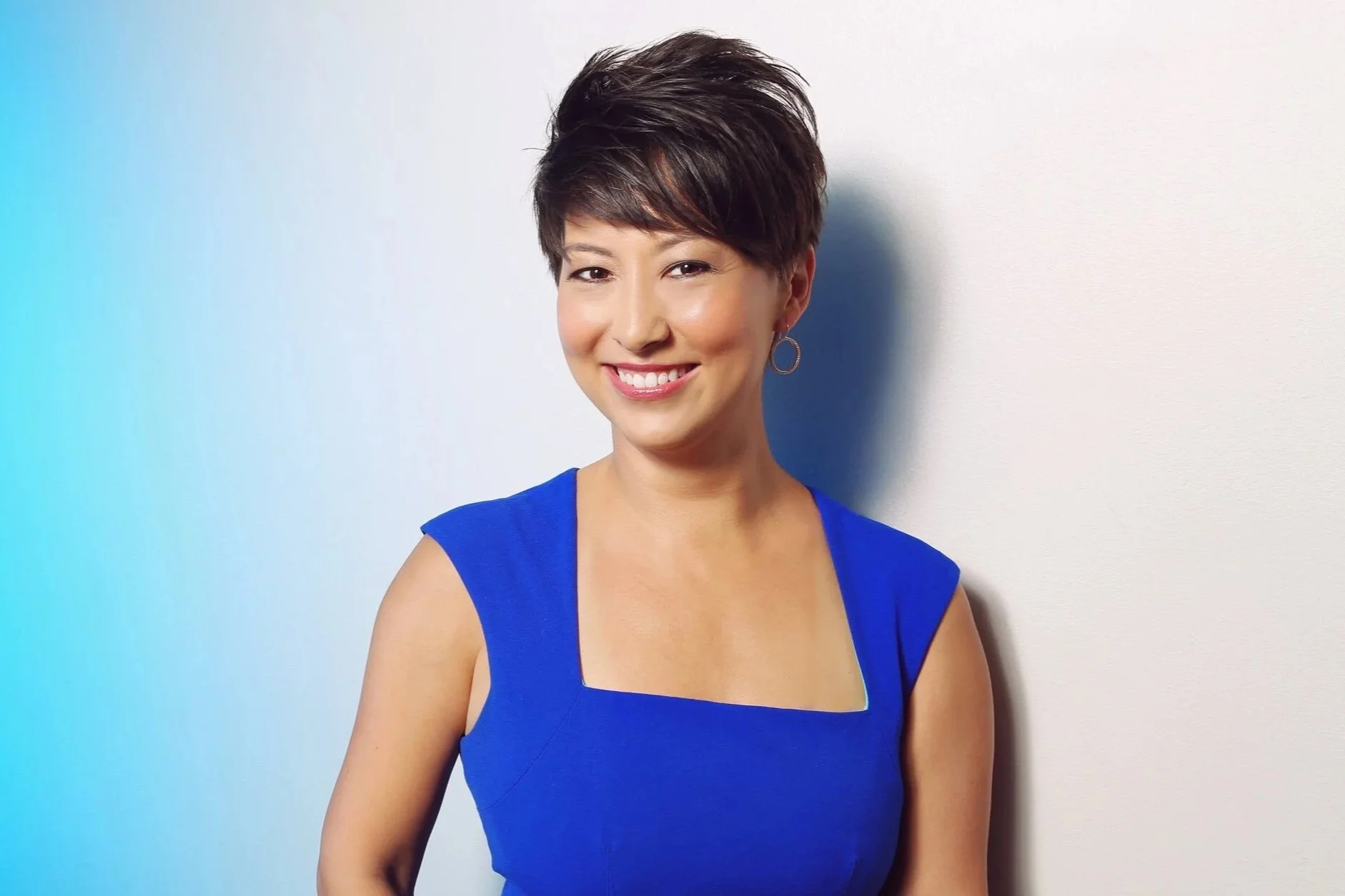 Headshot of Dr Cory Owen who has short brown hair, is wearing a bright blue dress, and is smiling at the camera