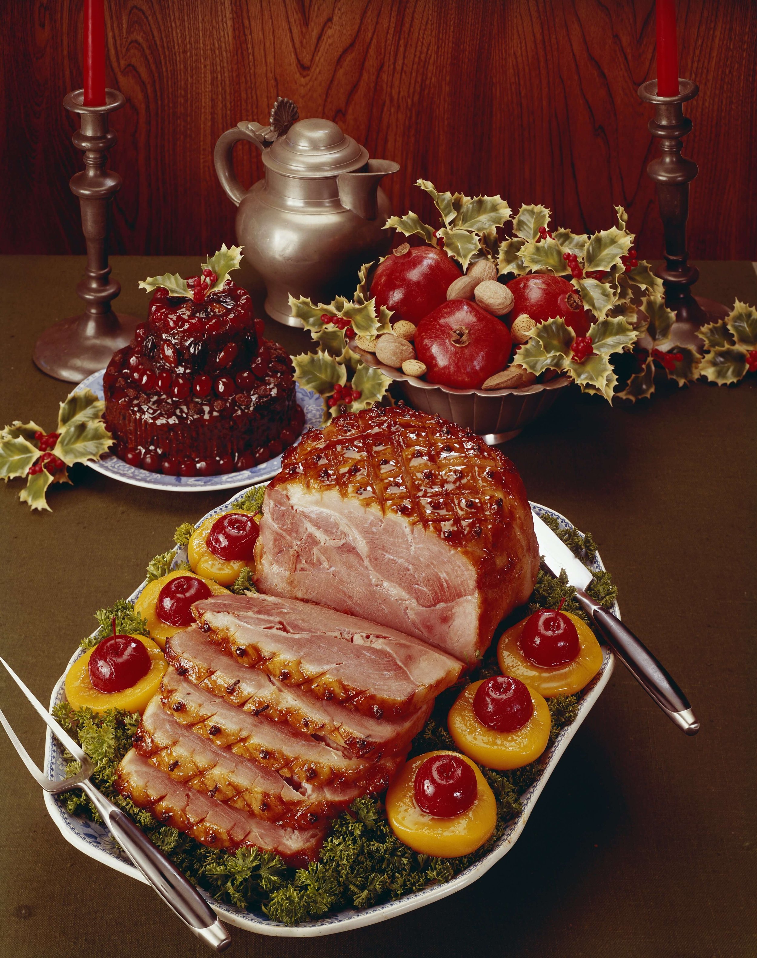 A vintage holiday dinner table of ham, jello, and pomegranates.