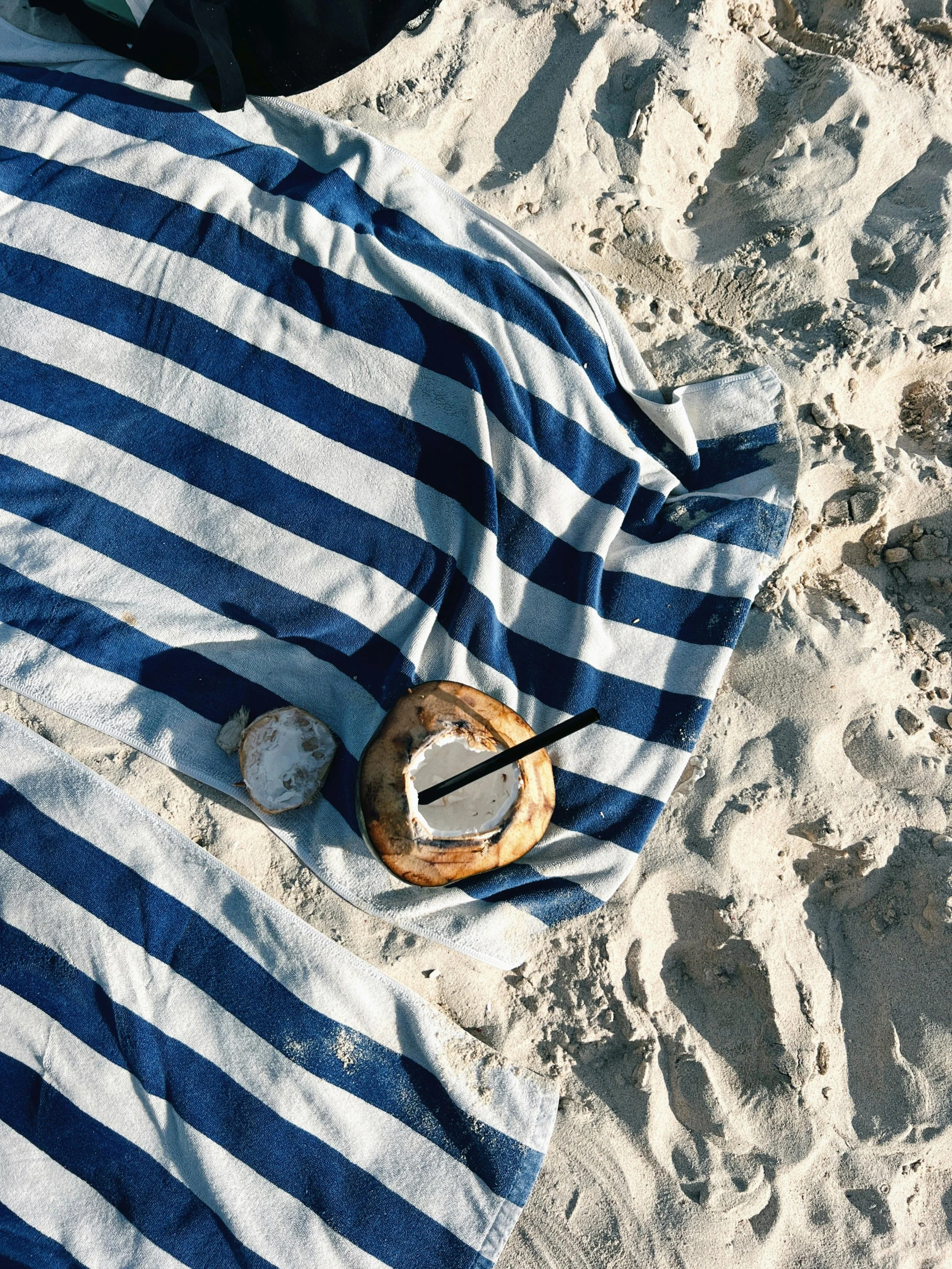 Sandy beach with towel and coconut