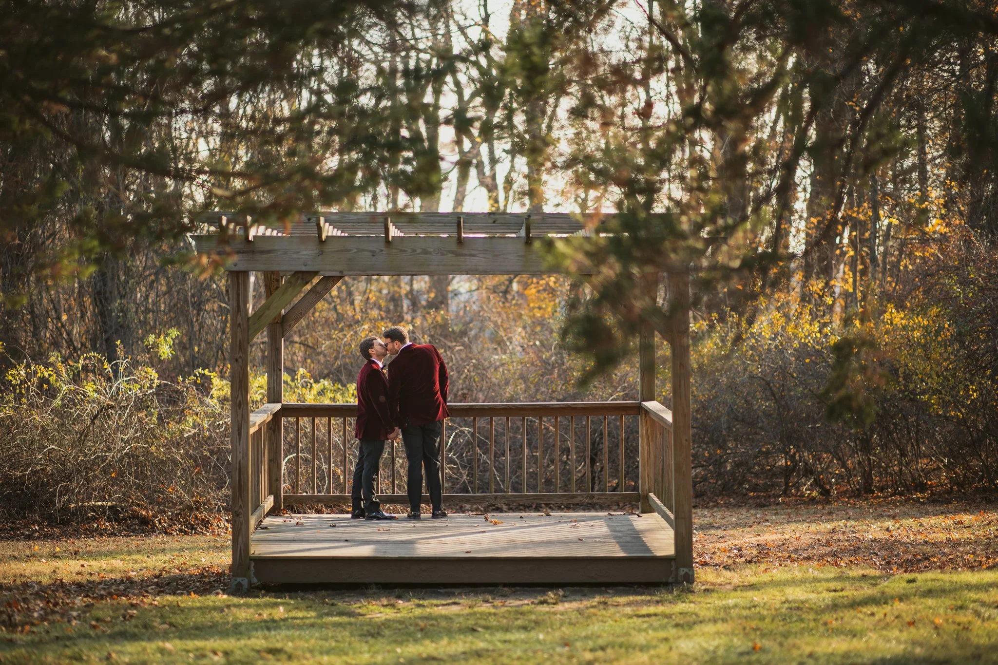 Two grooms share a kiss during golden hour portraits at Stevens Estate at Osgood Hill in North Andover, Massachusetts.