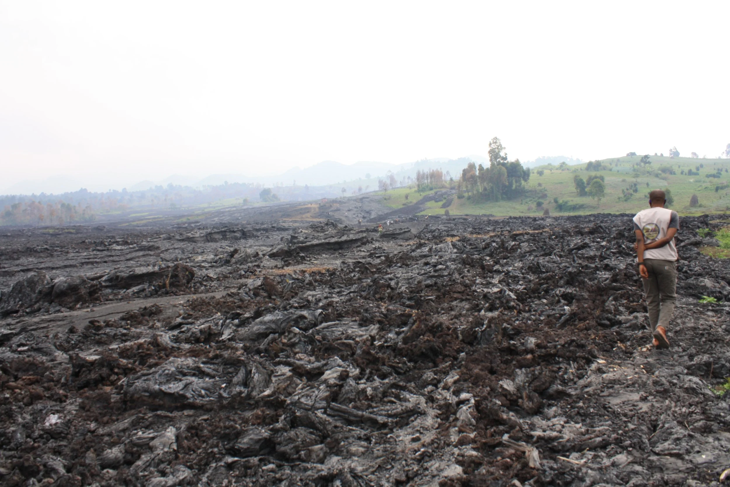  Volcanologists walk across hardened lava in Goma. They were measuring the width of new fissures that had cracked open in the earth in May. (Sophie Neiman, July 2021)  