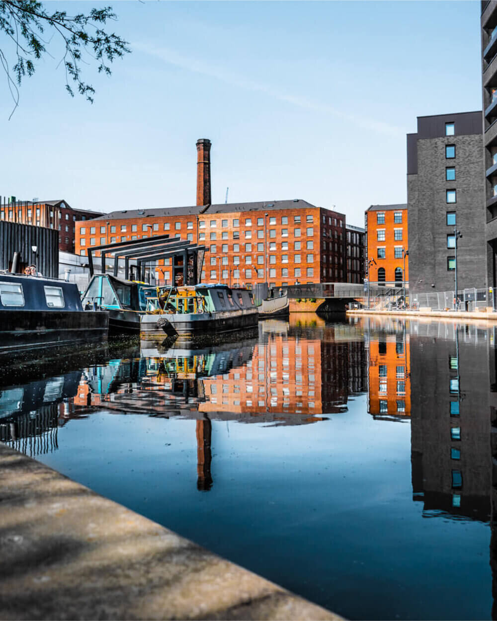 Orange brick mill reflected in the canal at New Islington Marina in Ancoats, Manchester