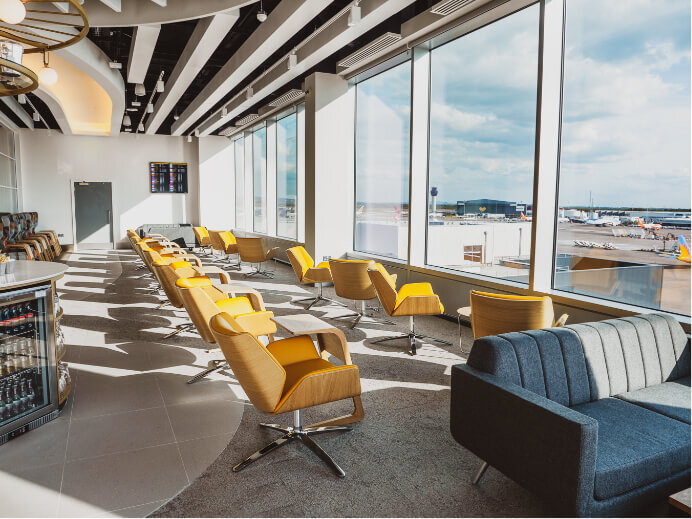 Manchester Airport premium 1903 Lounge show yellow chairs facing the runway with planes in the background