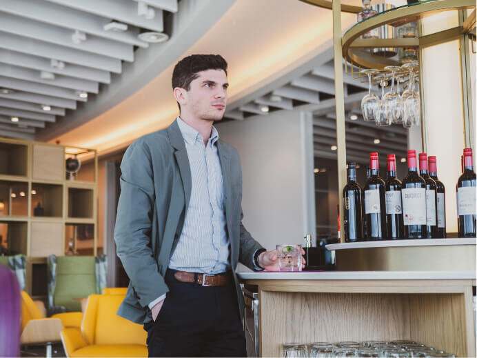 Portrait photography of a man standing next to an island bar inside a premium airport lounge