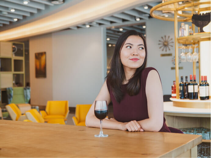 Portrait photography of an asian woman looking outside a window while enjoying a glass of red wine