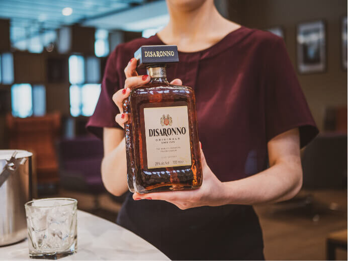 Photography of a waitress holding a bottle of Disaronno 