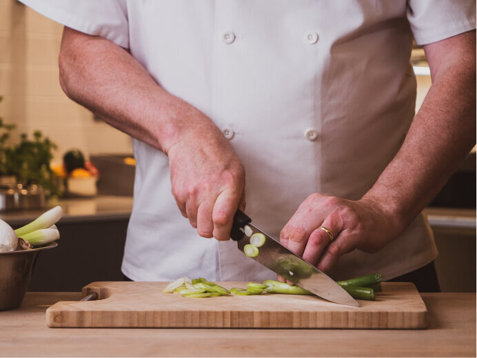 Photography showing a chef cutting a leak showing the precision that goes into food prep 