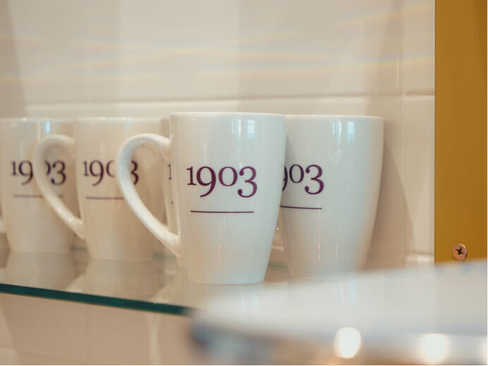 Close up of branded coffee mugs with 1903 branding