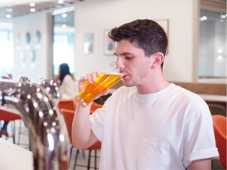 Young man taking a sip of beer inside Manchester Airport’s Escape Lounge