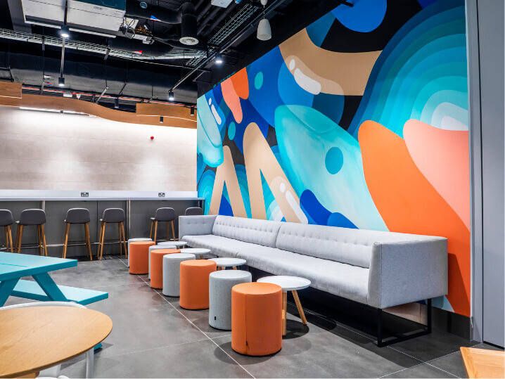 Reception area showing a vibrant abstract wall mural and comfy seating area for customers while waiting to enter the airport lounges