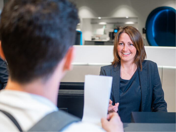 Reception staff smiling and greeting a customer for Manchester Airport’s airside lounges