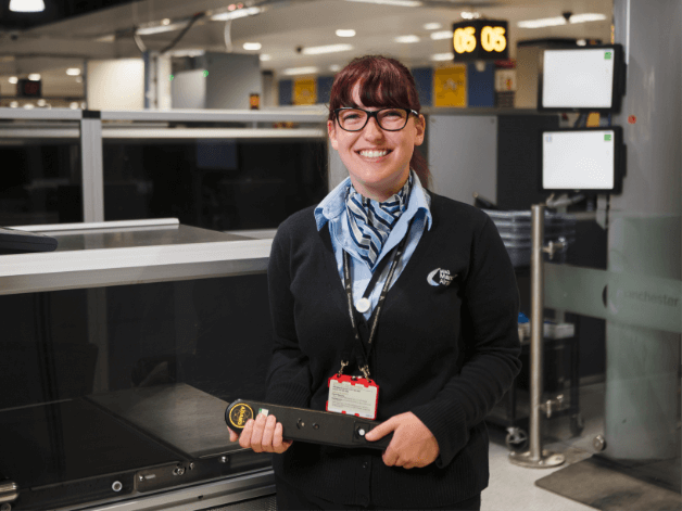 Happy young airport worker captured by the security gates at Manchester Airport