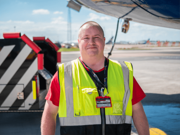 Smiling runway worker cleaning an airplane on a bright sunny day at Stansted Airport