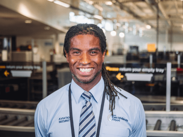 Staff portrait photography showing a smiling airport baggage worker