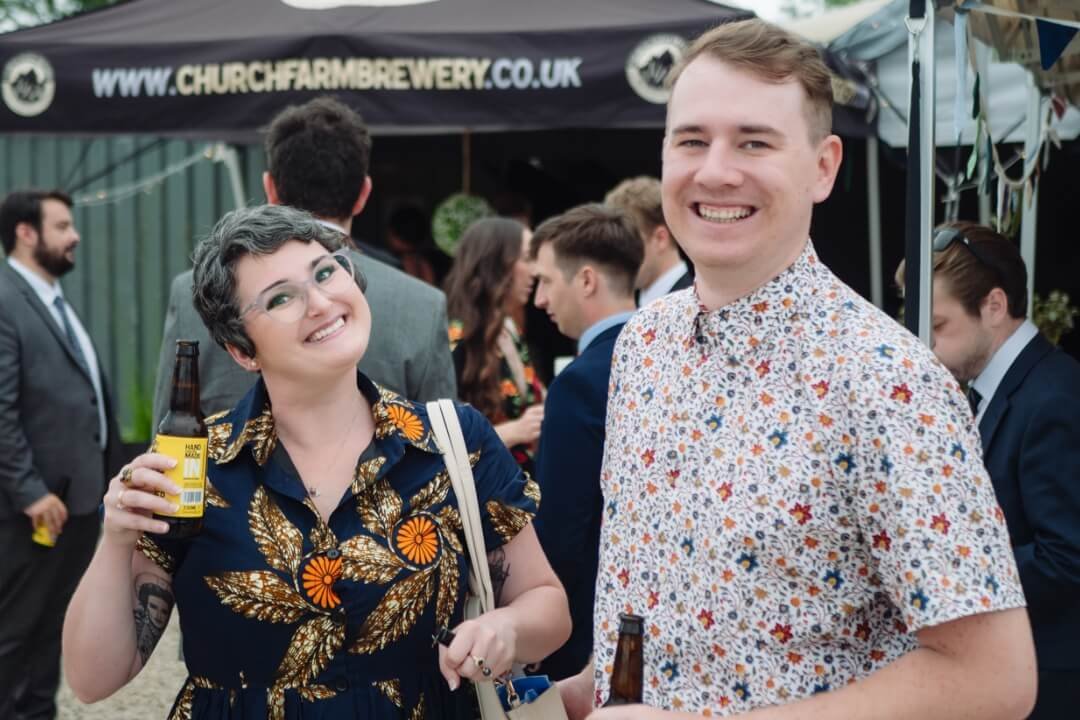 Guests smiling and holding drinks at outdoor wedding celebration