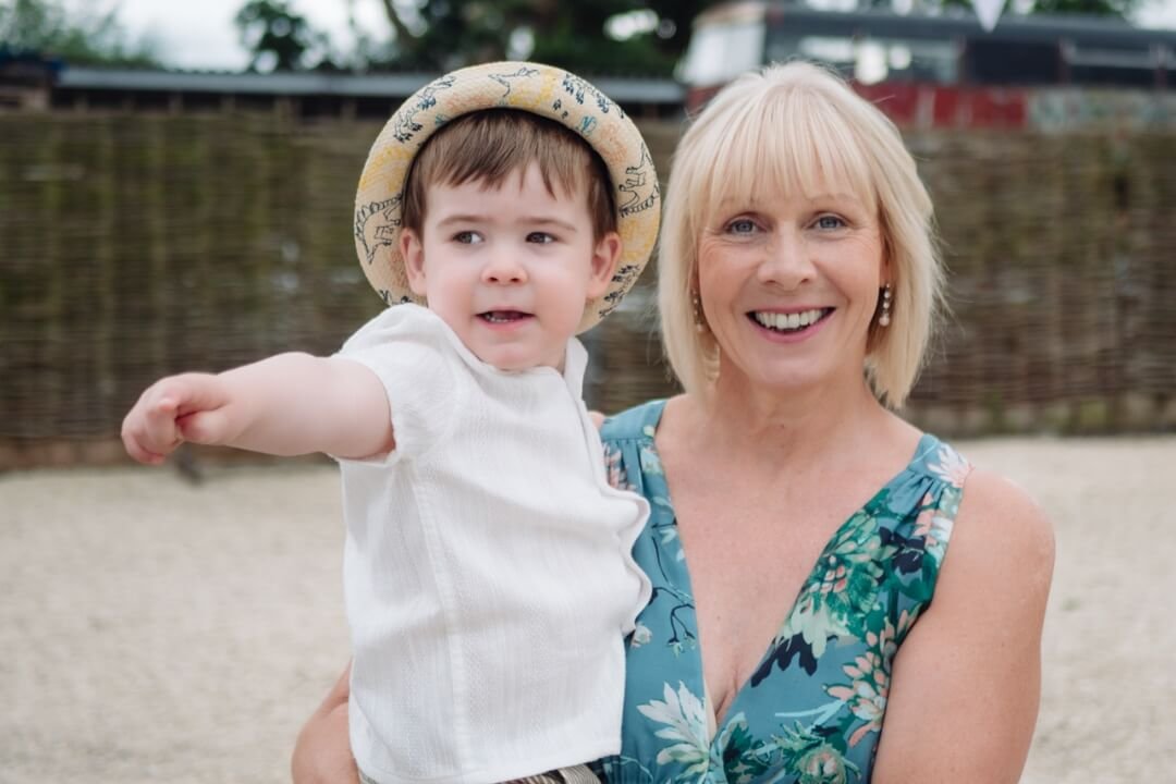 Young boy in hat with grandmother smiling outdoors at a wedding reception