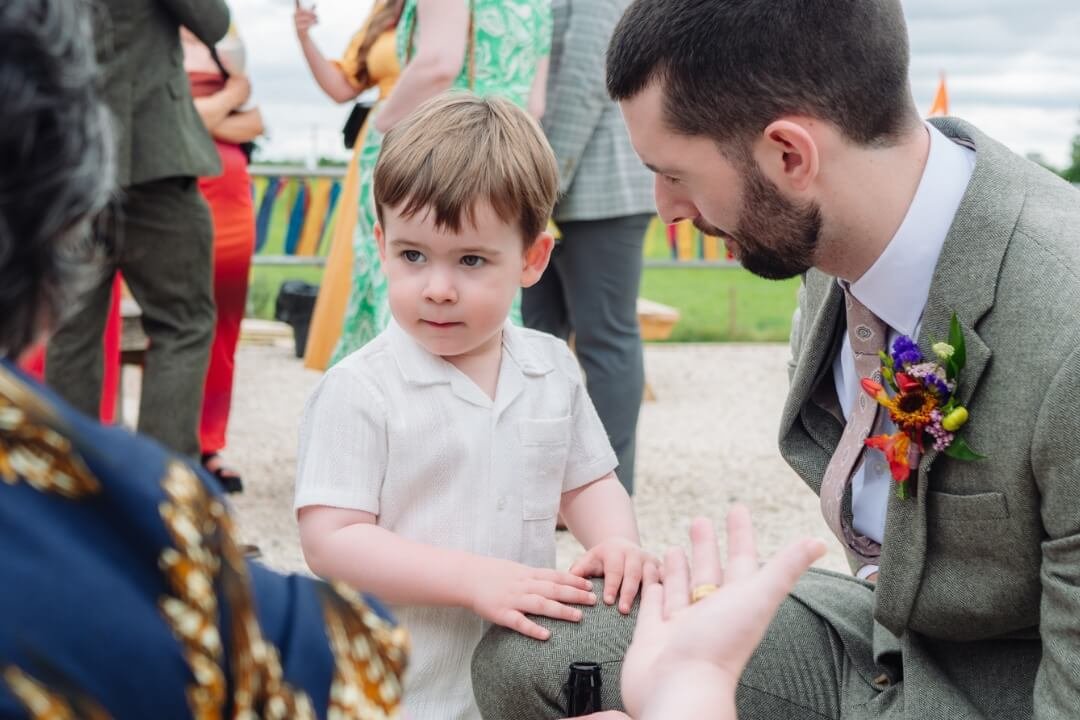 Groom kneeling and talking to his son during a wedding ceremony