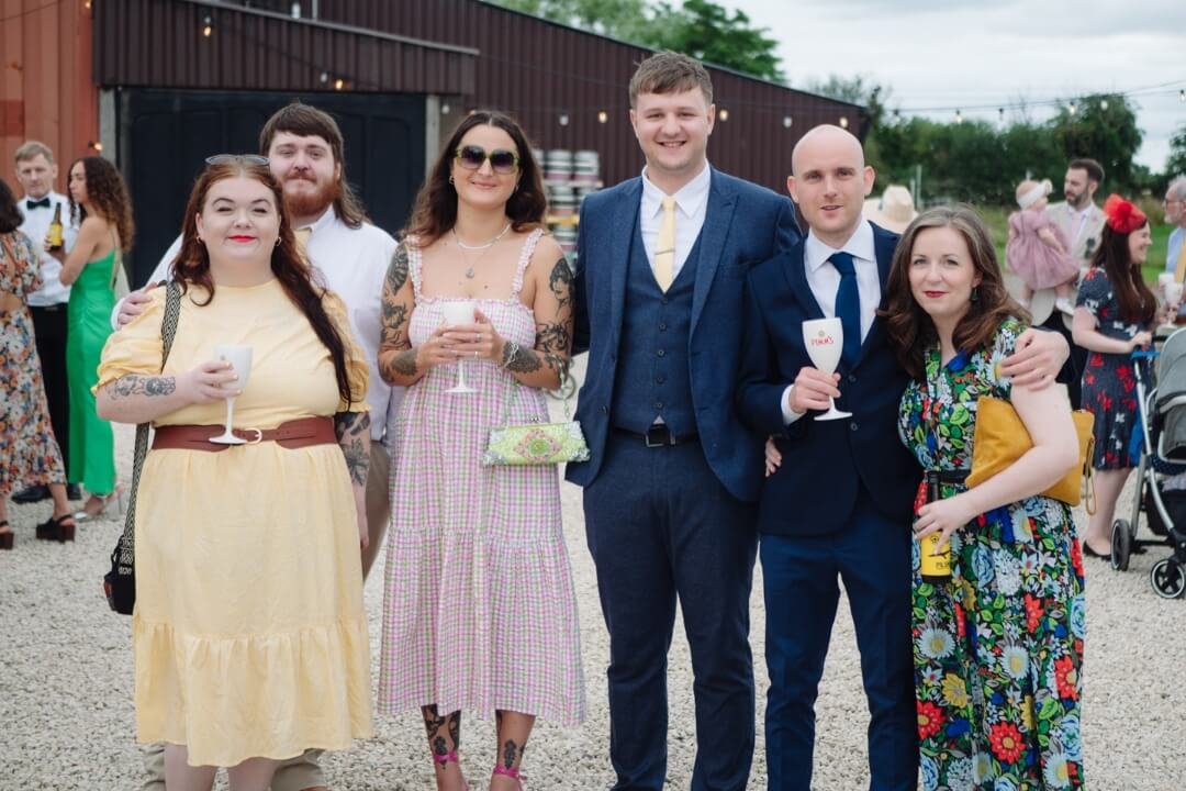 Group of wedding guests posing together, dressed in colourful attire