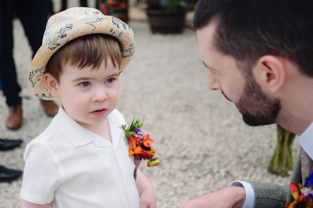 Father of the groom talking to young boy in outdoor wedding setting