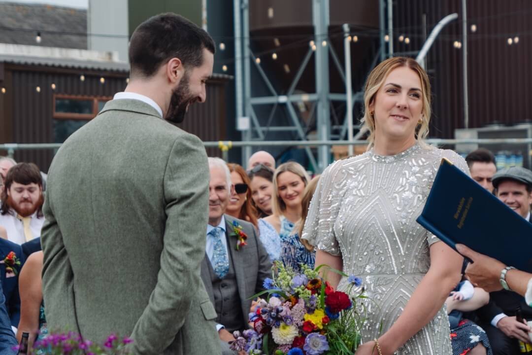 Bride and groom during wedding ceremony, exchanging smiles with guests