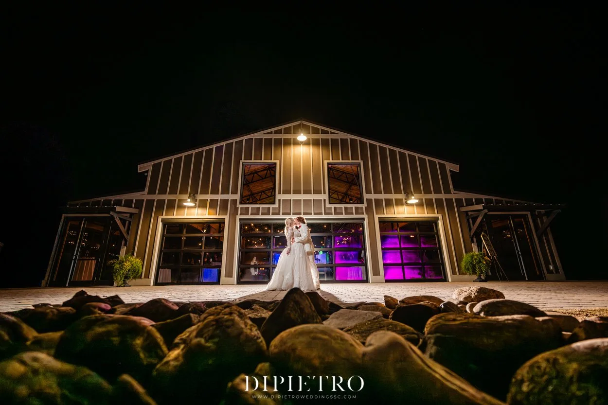 Couple standing outside The Barn at Sitton Hill with the barn illuminated at night