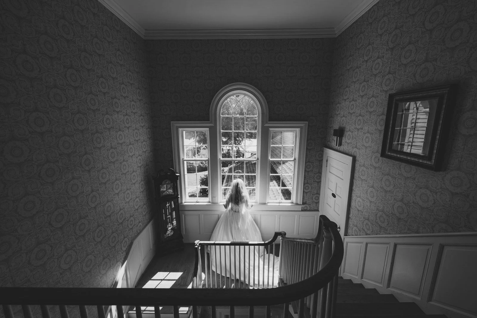 Black and white bridal portrait beside an arched window on the historic staircase at Duncan Estate in Spartanburg, SC.