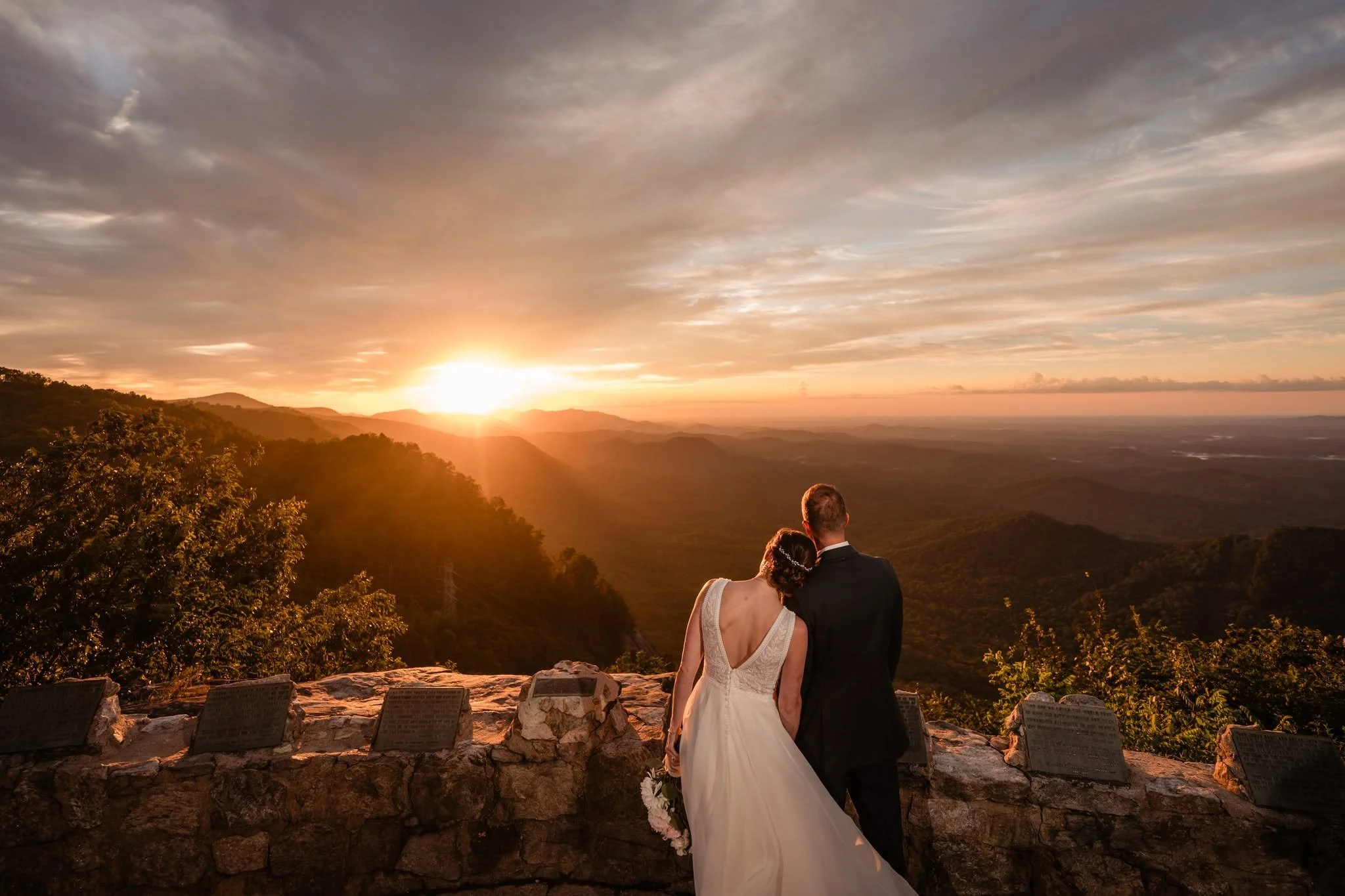 Bride resting her head on the groom’s shoulder at Pretty Place Chapel as they overlook the mountains at sunrise.