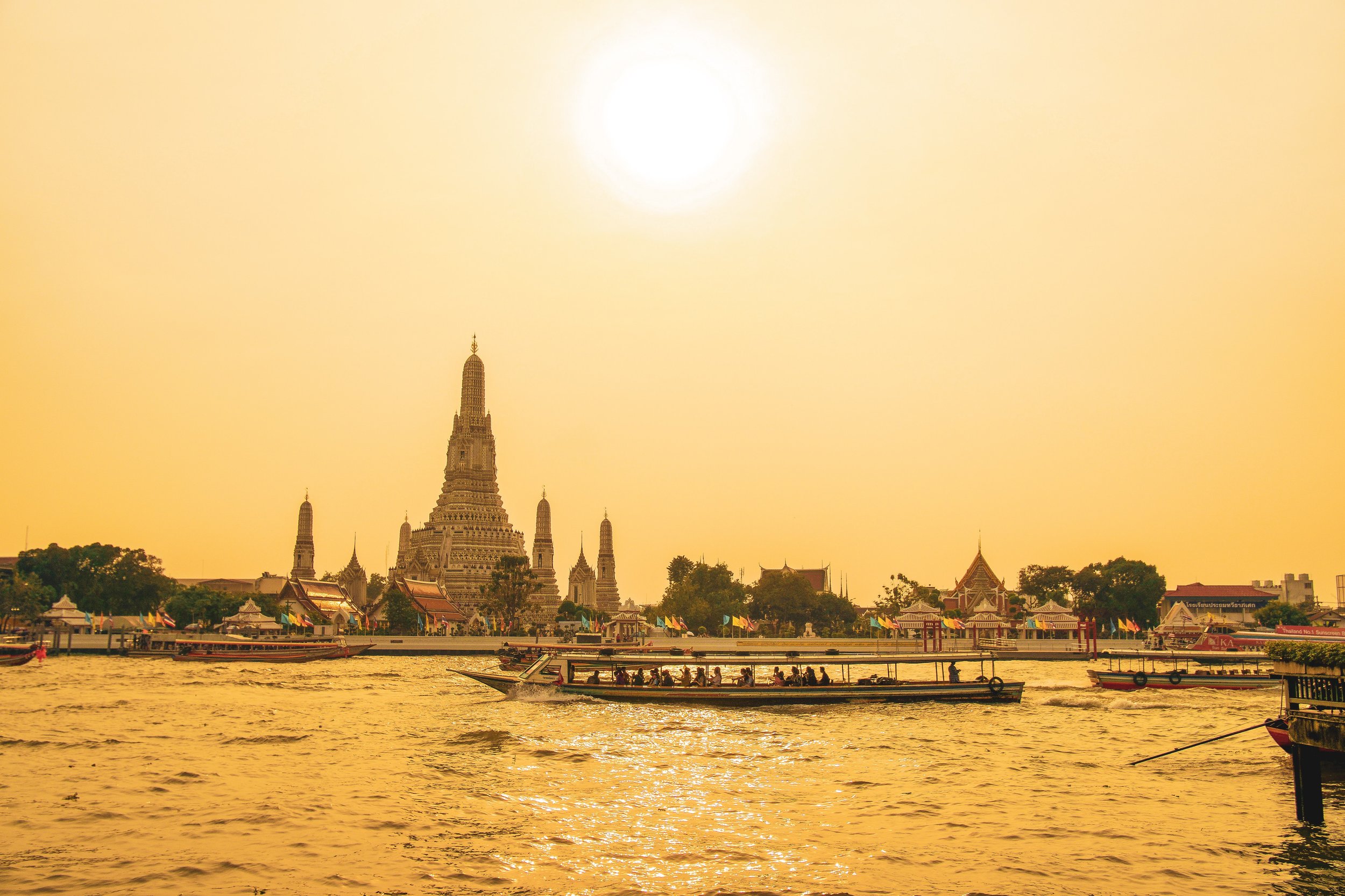 A boat on a river in thailand with temples in the background.jpg