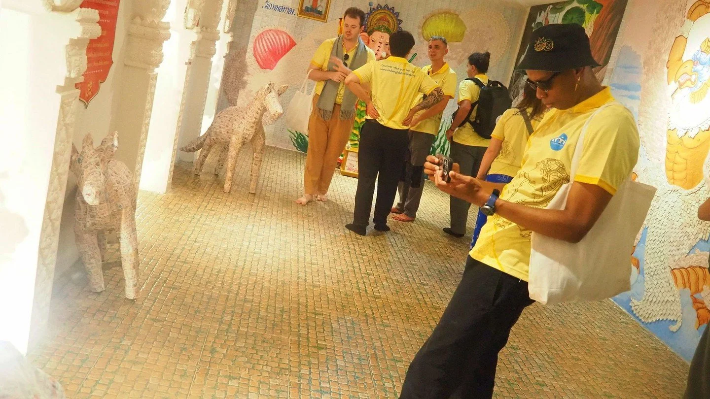 Temple day in Sukhothai just felt like stepping back in time! 

Teacher Devin walked barefoot through the ancient hall, yellow KET shirt bright against centuries-old murals, pausing to light incense and bow quietly beside statues wrapped in golden cl