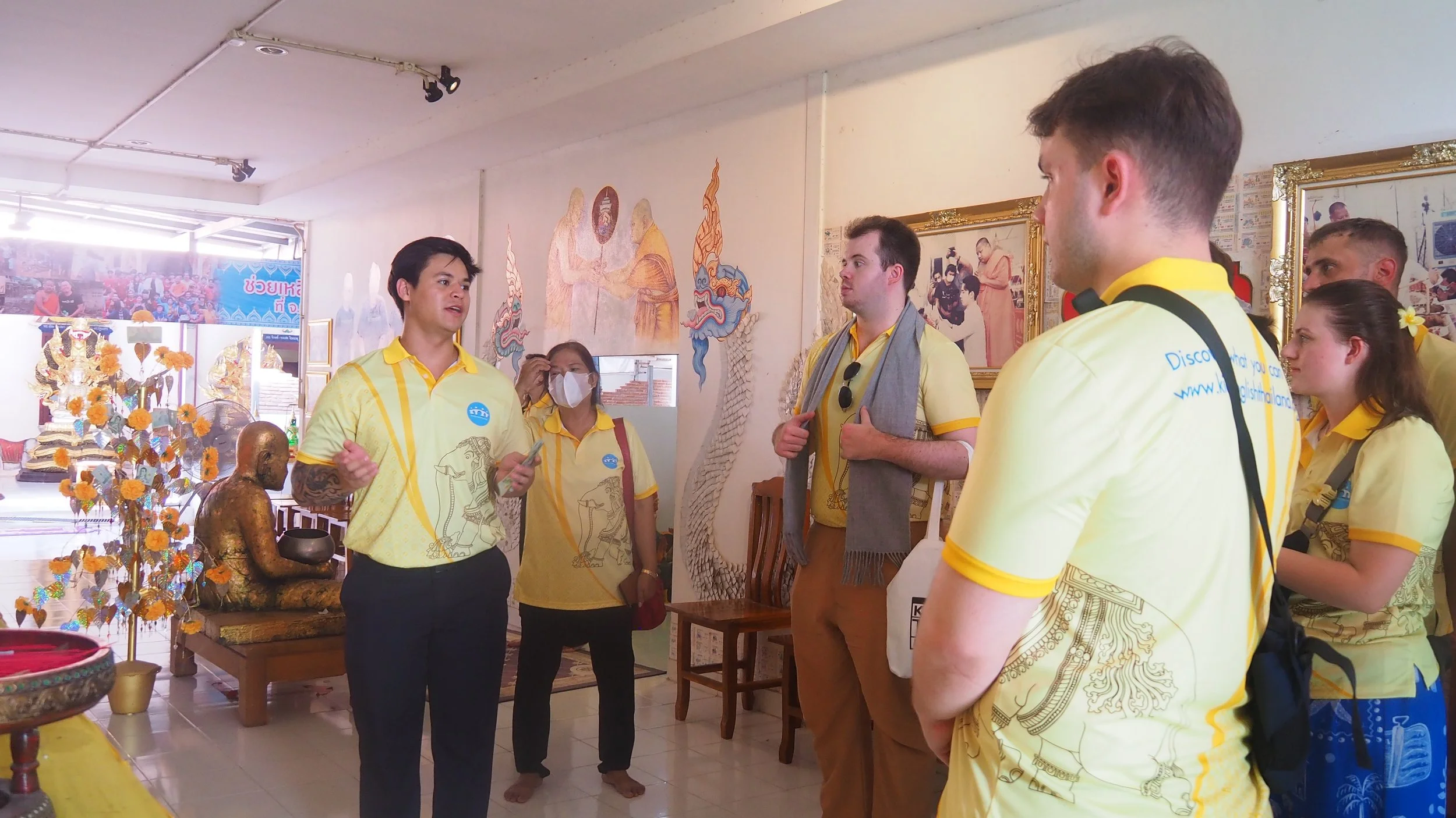 A KET representitive explaining Thai cultural artifacts to a group of tourists at a museum to Kids English Thailand teachers.