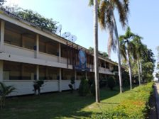 Kids English Thailand Image-The exterior of a two-story motel with a blue sign, surrounded by palm trees and a grassy area.