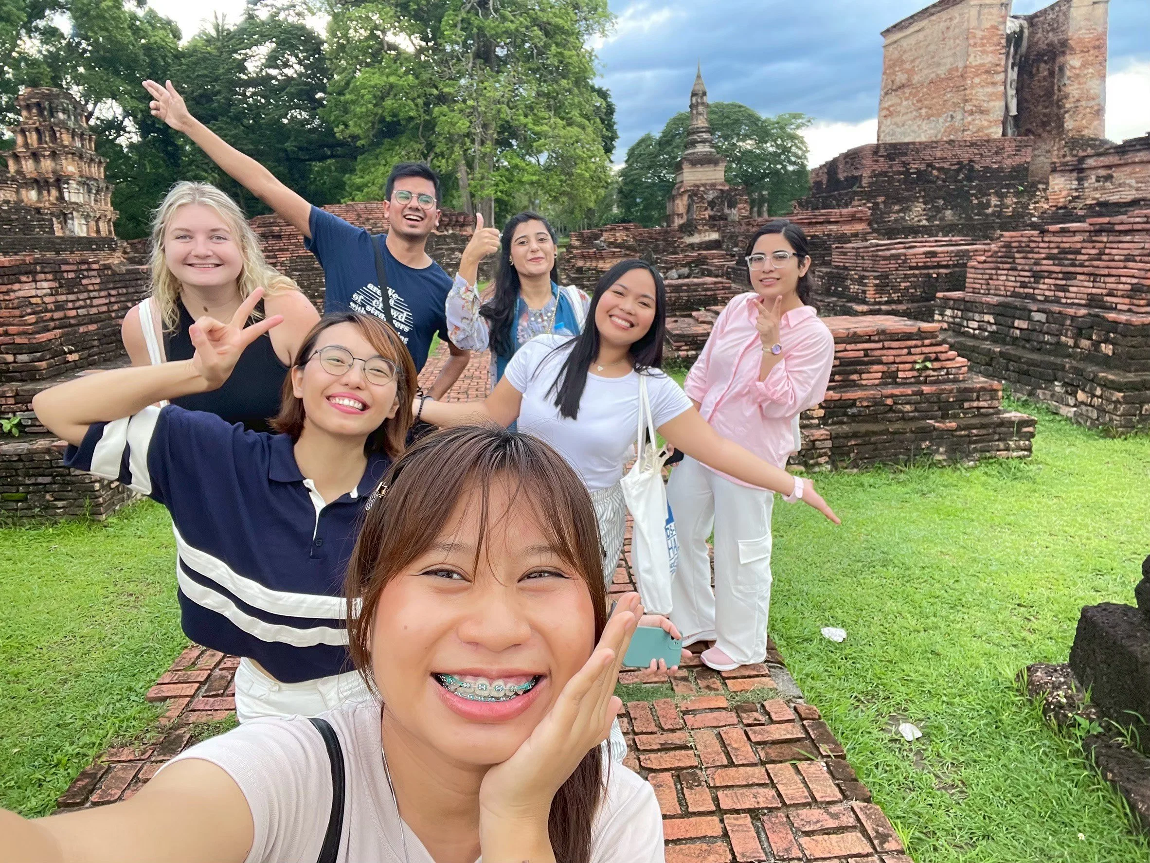 Group of Kids English Thailand teachers people posing for a selfie at historical ruins with brick structures and lush green trees