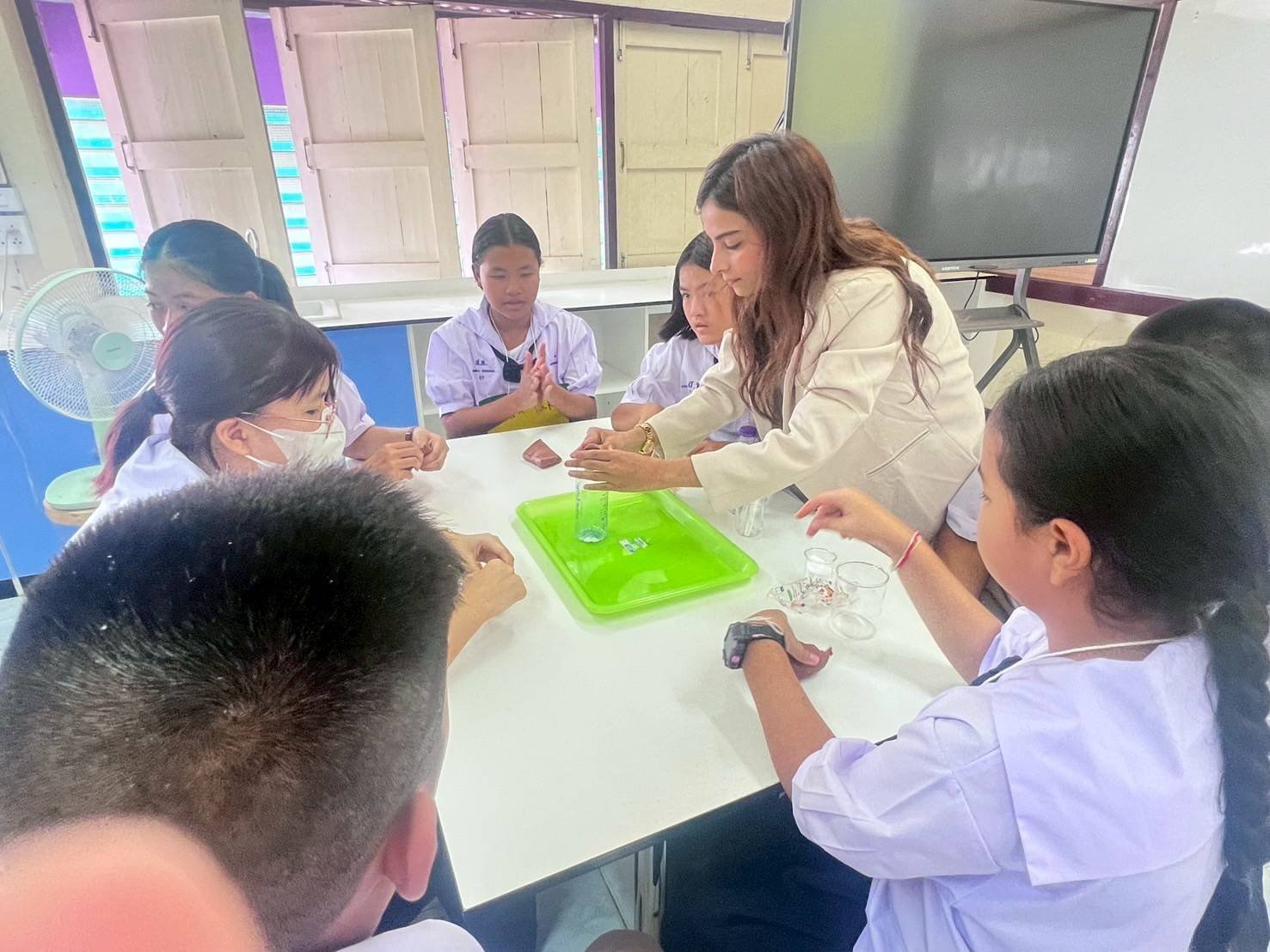 A Kids English Thailand teacher demonstrating a science experiment to students in a classroom.