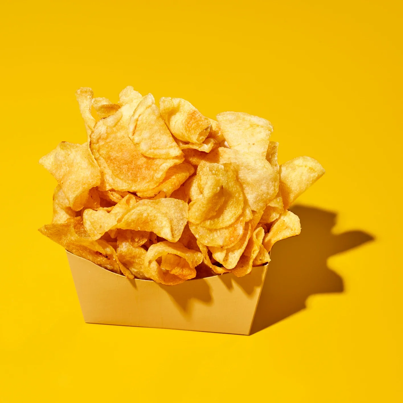 patatas fritas en un recipiente blanco sobre fondo amarillo