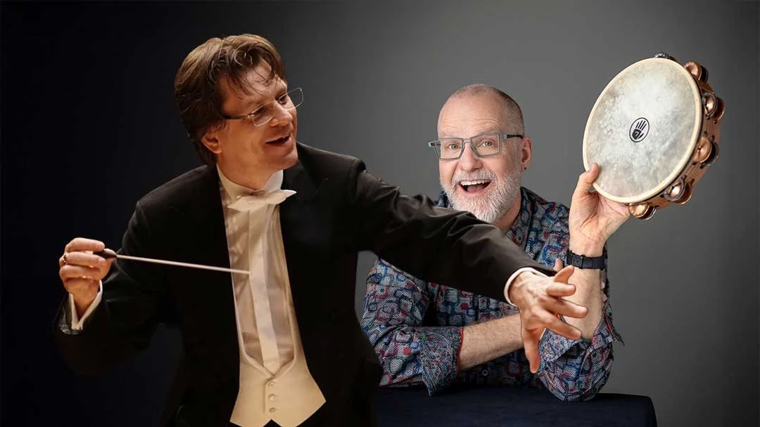 Photo of Martin Majkut conducting with baton, and Terry Longshore smiling with tambourine.