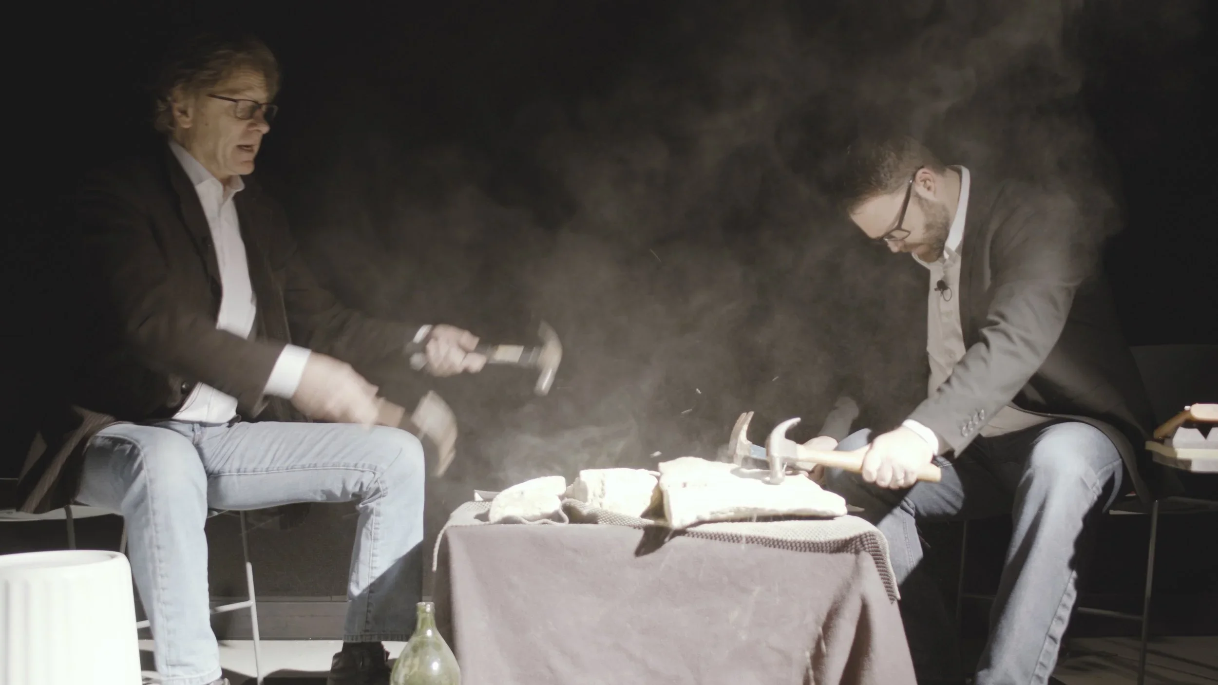 Photo of John Lane and Alan Otte hammering on stones, claw hammers in each hand. Dust is flying.
